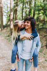Fototapeta premium Young romantic couple hugging, kissing and having fun while they have vacation in forest