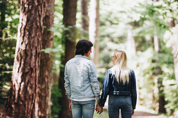 Fototapeta premium Young couple walking, hand in hand, through forest