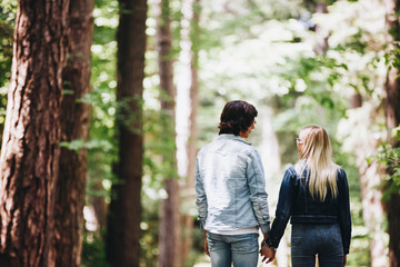 Fototapeta premium Young couple walking, hand in hand, through forest