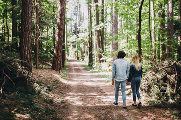 Young couple walking, hand in hand, through forest