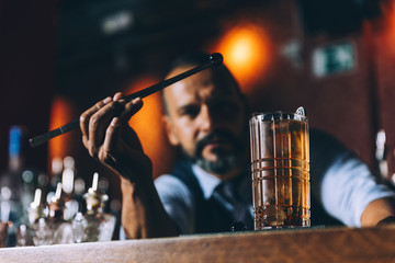 Barman is making cocktail at night club.