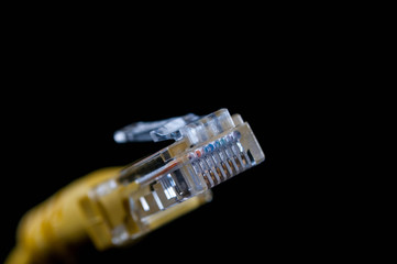 Yellow internet cable close up macro shot isolated on black background.