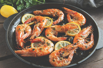 fried roasted shrimps in frying pan with lemon greens parsley garlic