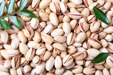 Pistachios background. Pistachio texture with leaves. Nuts. Top view