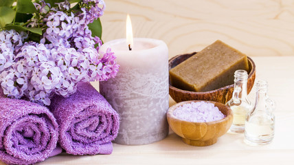 Fototapeta na wymiar Spa setting with lilac, towels and candle, still life of wellness spa