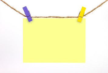 The blue and yellow wooden clip clamped the yellow note with the hemp rope.