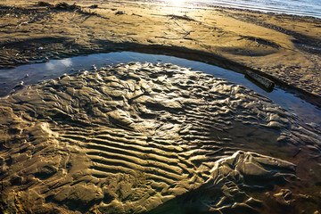 texture of sea sand with traces of waves and blue water