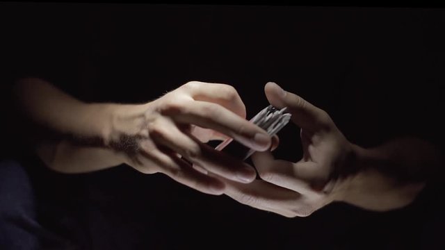 Close-up. Cards fly from one hand to another. The magician shows a card trick. Slow motion.