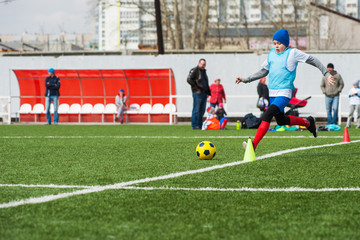 Boy kicking soccer ball on sports field