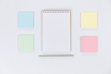 Notepad paper with sticky note and pencil on a white background.