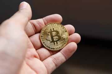 Fototapeta na wymiar A hand holding Golden bitcoin virtual money.