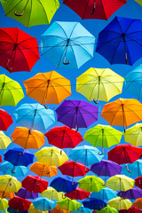 Fototapeta na wymiar Colorful umbrellas background. Coloruful umbrellas urban street decoration. Hanging Multicoloured umbrellas over blue sky. umbrellas with many colours.