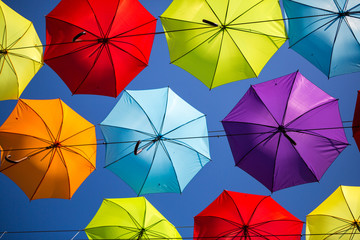 Colorful umbrellas background. Coloruful umbrellas urban street decoration. Hanging Multicoloured umbrellas over blue sky. umbrellas with many colours.