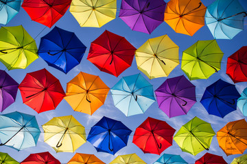 Colorful umbrellas background. Coloruful umbrellas urban street decoration. Hanging Multicoloured umbrellas over blue sky. umbrellas with many colours.