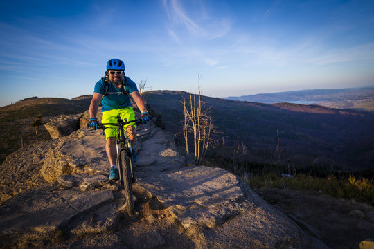 Mountain biker riding on bike in summer mountains forest landscape. Man cycling MTB flow trail track. Outdoor sport activity.