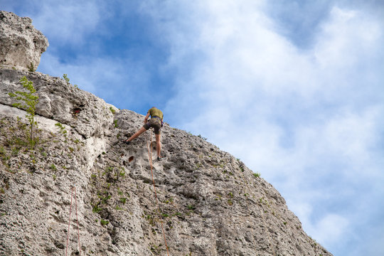 Abseiling from a rock. Man comes down from peak.