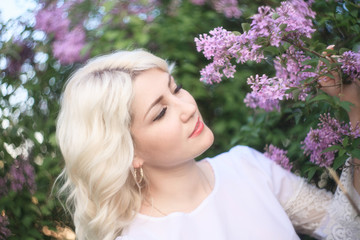 Beautiful woman in a spring garden with blooming lilacs.