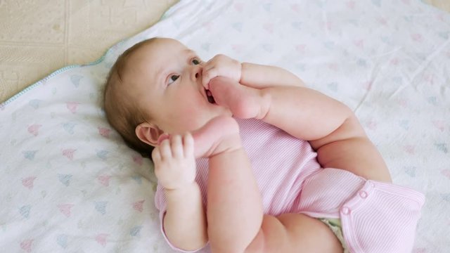 baby girl in pink clothes lying on her back on a diaper in bed