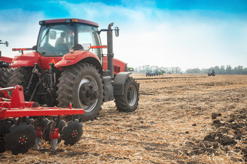 Fototapeta premium Red tractor in the field on a bright sunny day.