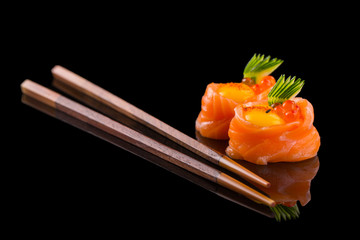 fresh salmon sushi with egg yolk and caviar on the black background