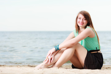 Happy woman sitting on beach near sea