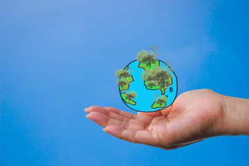 A woman's hand with a globe created from a painting with a tree in the forest. Nature Conservation Concepts