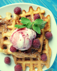 Plate of belgian waffles with ice cream and fresh berries over blue wooden background