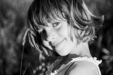 portrait outdoors at sunset of a beautiful kid girl among the flowers. Black and white photography....