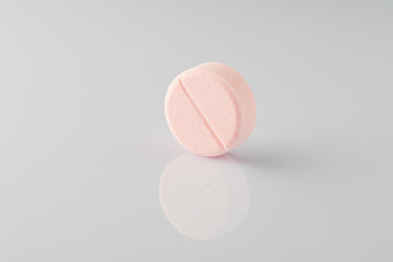 pink medical ascorbic pill on a light background with reflection. Isolated 