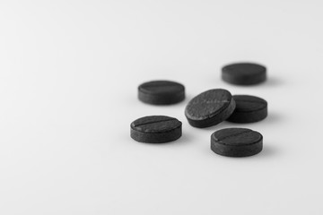 several black medical activated charcoal pills on white background. Isolated