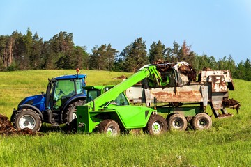Natural manure agro bio fertilization. Loading manure onto tractor. Agricultural landscape in the Czech Republic.