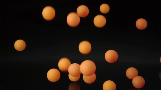 Slow motion orange balls falling and bouncing on black background