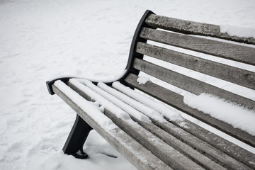 wood bench close up covered by white snow on the floor with snow