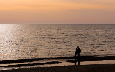 Fototapeta premium A hugging couple on a sunset background over the sea.