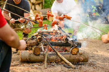 Grilling sausages over a campfire in the forest. Holiday and summer camping in the countryside. Beltaine night in the Czech Republic. May day celebrations. 