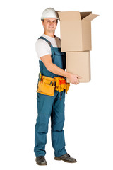 male builder or manual worker in helmet holding pile of cardboard boxes over white wall background. repair, construction, building, people and maintenance concept