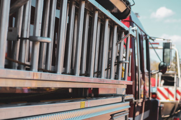 Ladder strapped to the side of a fire truck while a lone cloud floats beyond in the blue sky