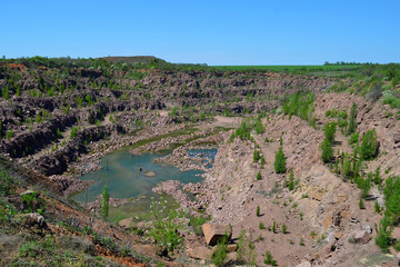 Stone quarry with lake at the bottom in sunny weather