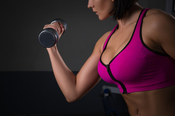 Fototapeta na wymiar athletic young woman doing a fitness workout with dumbbells on black studio background. Halthy concept