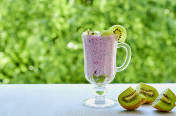 Chia pudding in the glass with sliced fresh kiwi fruit. Detox superfoods breakfast or healthy dessert with copy space on the natural green background. Side view