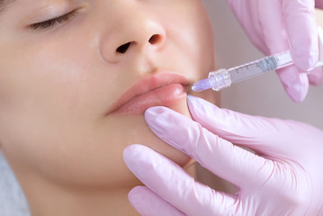 The doctor cosmetologist makes Lip augmentation procedure of a beautiful woman in a beauty salon.Cosmetology skin care.