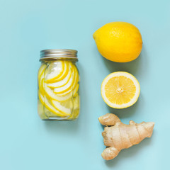 Healthy detox water with ginger and citrucs in mason jar on punch blue background. Wellness.