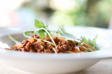 spaghetti Bolognese with minced beef and tomato sauce garnished with parmesan cheese and basil , Italian food