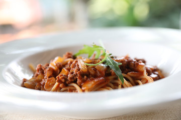 spaghetti Bolognese with minced beef and tomato sauce garnished with parmesan cheese and basil , Italian food