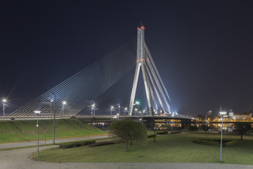 Fototapeta premium Vansu Bridge in Riga, Latvia. Shroud Bridge. Summer night With Blue Sky. 595 Meters In Length. Vansu Bridge - One Of The Symbols Of Modern Riga. Old Town of Riga and River Daugava at night.