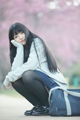 Japanese school girl dress sitting with sakura flower nature walkway