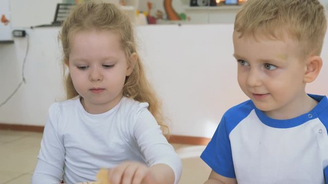 Children's developing a game room. Emotions of young children during entertaining classes. Boys and girls are playing with wooden blocks sitting at the table.