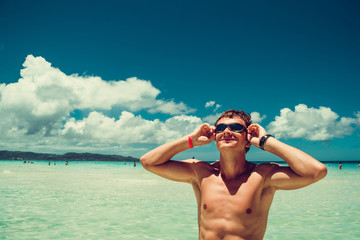 Happy smiling man in swimming goggles enjoying summer beach vacation. Time to travel. Stress free. Looking up sky. Shirtless fit athletic male body. Exotic luxury holiday. Tourism concept. Copy space