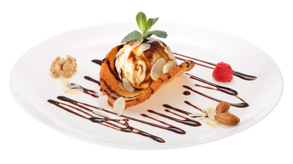 Ice cream ball decorated with chocolate syrup, nuts, raspberries, mint leaves and coconut chips on a wafer of coconut and honey. All on white plate isolated on white background.