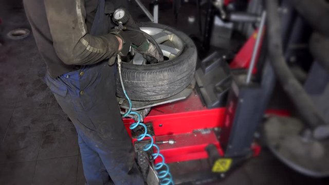 man inflate tire air on mounting machine.